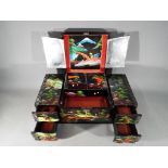A Japanese lacquered, musical jewellery box with hand painted landscape decoration,