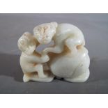A Chinese white jade or hardstone carving depicting two monkeys and a peach, leaf design to base,