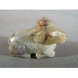 A Chinese grey-green jade carving of a recumbent goat, with russet inclusions,