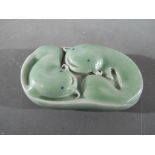 A Chinese celadon glaze scroll weight depicting a pair of catfish, seal mark to the base,