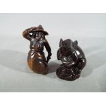 A vintage Japanese dark wood Netsuke depicting a large mouse or rat carrying its catch,
