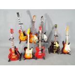 Eight detailed, miniature models of guitars, with stands.