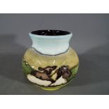 Moorcroft Pottery - a vase decorated with images of spring lambs, approx 10 cm (h).