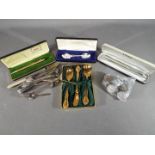 A mixed lot to include a plated sugar nips, plated spoons in presentation cases,