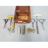 A wooden box containing vintage corkscrews, padlocks and similar.