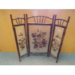 A decorative bamboo and glass three fold fire screen, the glass panels with floral decoration,