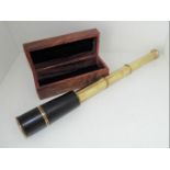 A leather bound, three-draw brass telescope, in hinge-lidded hard wood case, the case measuring 5.