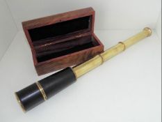A leather bound, three-draw brass telescope, in hinge-lidded hard wood case, the case measuring 5.