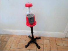 A traditional bubble gum machine with metal body, stand and glass dome.