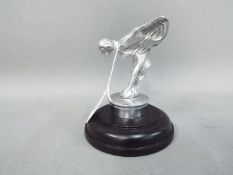 A chrome 'Flying Lady' mounted on a wooden base,