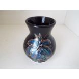 Anita Harris - a vase decorated with irises on a black ground, signed to the base,