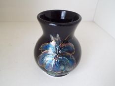 Anita Harris - a vase decorated with irises on a black ground, signed to the base,