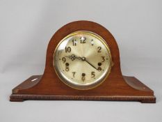 A Napoleons hat mantel clock with carved detailing, Arabic numerals to the dial, with pendulum.