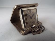 An Art Deco cushion styled purse watch or small travelling clock,