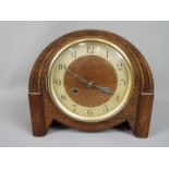A wood cased mantel clock with carved detailing, Arabic numerals to a chapter ring,