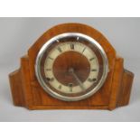 A wood cased mantel clock with Roman numeral chapter ring,
