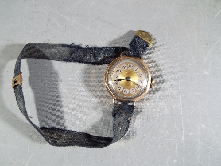 A 9 ct gold cased lady's wristwatch, stamped 9 and .375, on fabric strap, approximately 14.