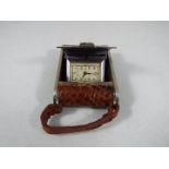 A small purse watch/ travelling clock, white metal and brown leather in the form of an early camera,