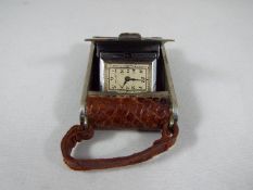 A small purse watch/ travelling clock, white metal and brown leather in the form of an early camera,