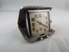 A small folding purse watch/ clock in a white metal cushion form case 36mm square engine turned Art