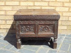 An antique storage chest highly carved with hinged lid 44 cm x 55 cm x 44 cm