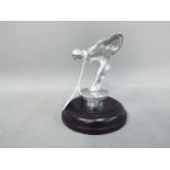 A chrome 'Flying Lady' mounted on a wooden base,