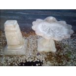 A reconstituted stone bird bath in the form of a shell and a garden ornament