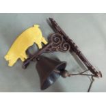 A wall mountable, cast iron bell surmounted with a depiction of a pig.