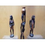 Three wooden African tribal carvings comprising a pair depicting a male and a female figure