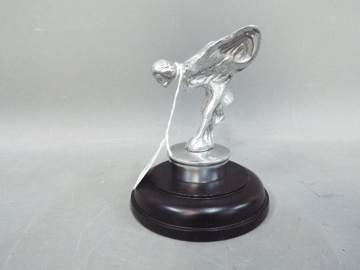 A chrome 'Flying Lady' mounted on a wood