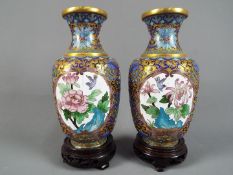 A pair of Chinese cloisonné enamel vases decorated to each side with panels of flowers and birds on