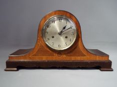 A mahogany and inlaid case Napoleons hat style mantel clock, silvered dial with Arabic numerals,
