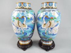 A pair of Chinese cloisonné vases decorated with flowers and swimming swans,