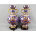 A large pair of Chinese cloisonné twin handled vases with raised foot decorated with five clawed