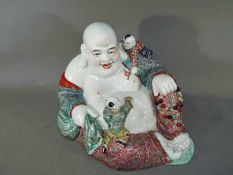 A rare Chinese famille rose laughing Buddha holding prayer beads, with two attendants,