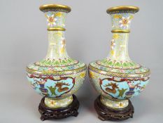 A pair of Chinese cloisonné enamel vases decorated to the body with panels of auspicious and