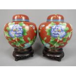 A pair of Chinese cloisonné ginger jars with floral decoration on a red ground,