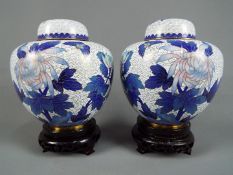 A pair of Chinese cloisonné enamel ginger jars and covers decorated with chrysanthemum on a white