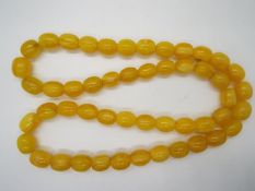 A string of egg yolk amber beads comprising 50 oblong shaped beads approximately 18 mm x 14 mm,