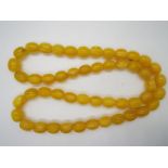 A string of egg yolk amber beads comprising 50 oblong shaped beads approximately 18 mm x 14 mm,