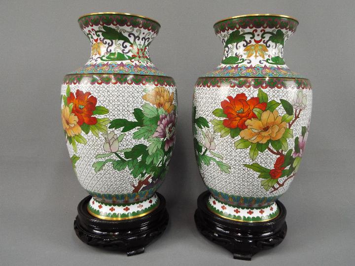 A pair of Chinese cloisonné vases decorated with flowers, birds and insects on a white ground,