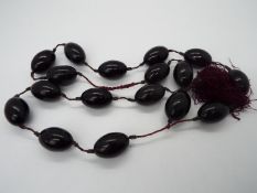 A strand of 17 cherry amber beads, each oval shaped bead approximately 30 mm x 19 mm,