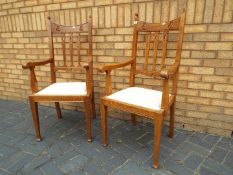 A pair of oak high back chairs with upholstered seats and arm rests