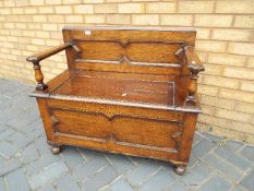 A oak monks bench with hinged lid opening for storage,
