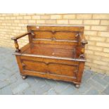 A oak monks bench with hinged lid opening for storage,