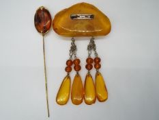 An amber brooch with four drop pendants and a hatpin, 38 grams all in.