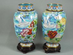 A pair of Chinese cloisonné vases with depictions of swimming swans set amongst flowering plants,