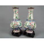 A pair of Chinese cloisonné enamel bottle vases decorated with peach branches and flowers on a