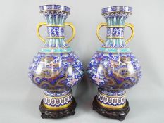 A large pair of twin handled Chinese cloisonné vases on raised foot,