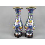 A pair of Chinese cloisonné baluster form vases with elongated neck decorated with scrolling